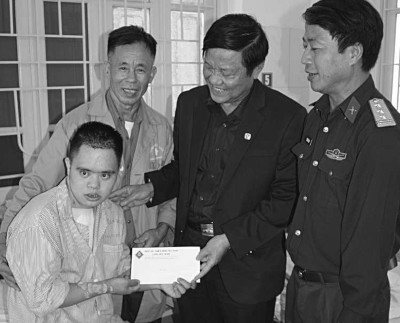 Dorfdirektor Long überreicht dem frisch operierten Nguyen Du Tho und seinem Vater die von Mitmachen Ehrensache für die Herz-OP bereitgestellte Spende