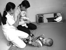 Die vietnamesische Therapeutin zeigt einer Mutter mit einer Puppe das physiologisch richtige Halten ihres behinderten Babys 